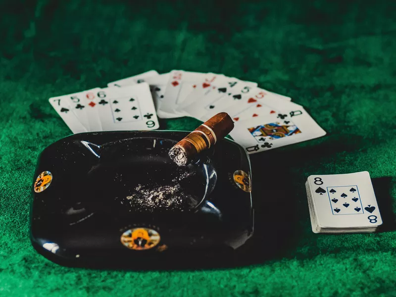 Cigar in ashtray with playing cards