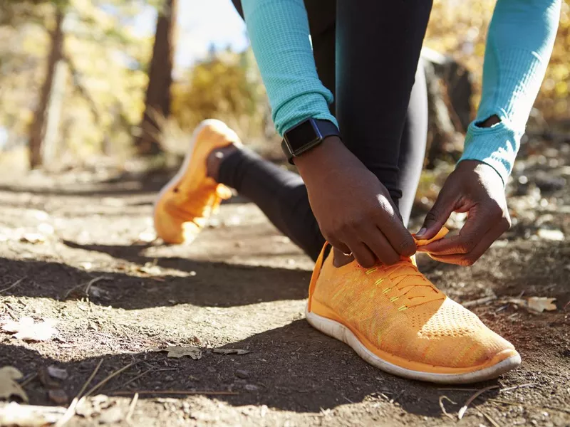 Runner in forest tying shoe