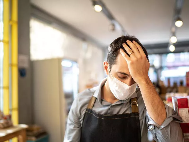 Worried owner with face mask at his small business