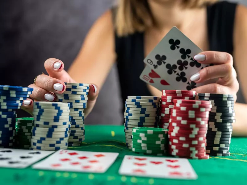 Woman taking poker chips from pile at round poker table