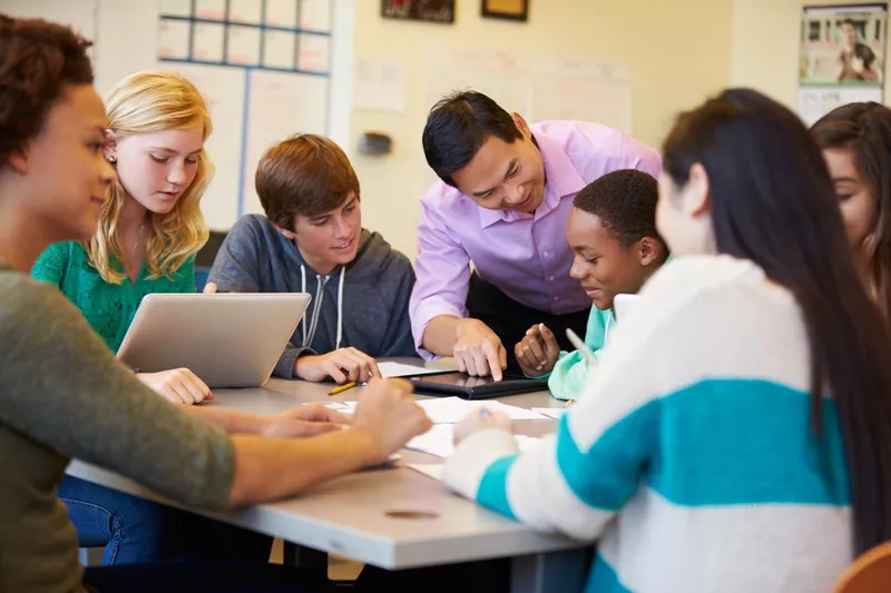 High school students with teacher in class using laptops