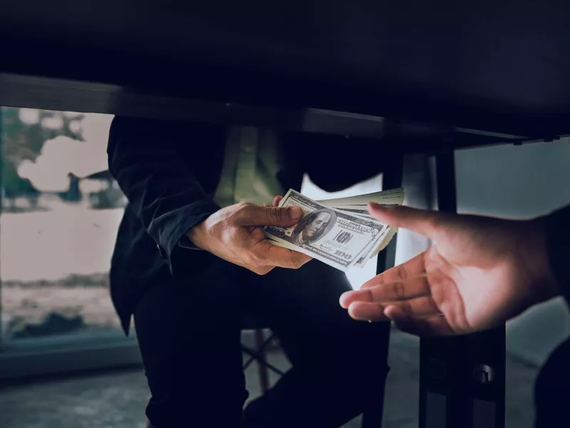 Businessman passing money under the table.