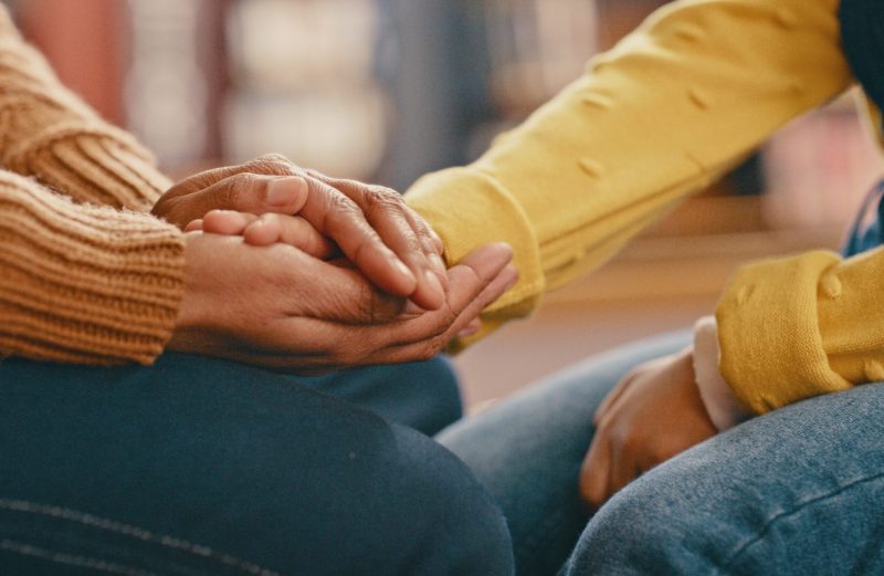 Hands, love and care touching in support, trust or unity for community, compassion or understanding. People holding hands in respect for loss, affection or passion for listening, talk or time