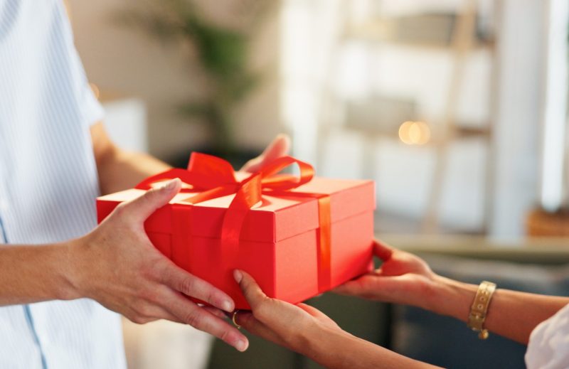 Love, gift and giving with hands of couple for valentines day celebration, box or bonding. Relationship, care and romance with man and woman at home for support, connection or present together