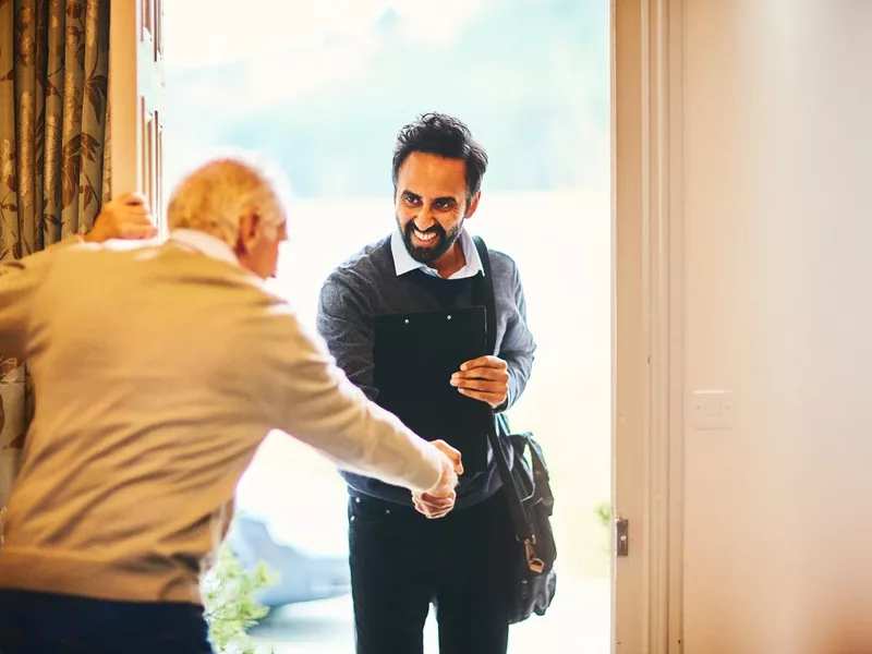 Senior man welcoming a healthcare social worker