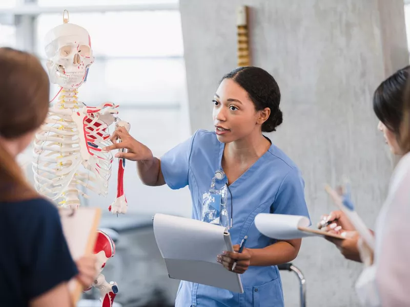 Young woman teaches class on human bone structure