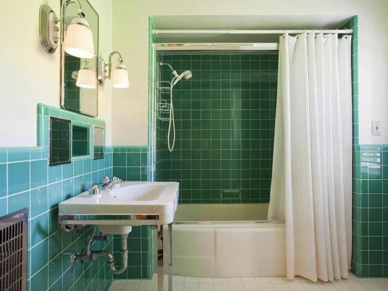 Green tiled bathroom with white suite and shower curtain