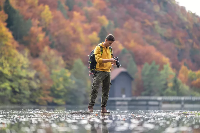 Male photographer holding camera in lake