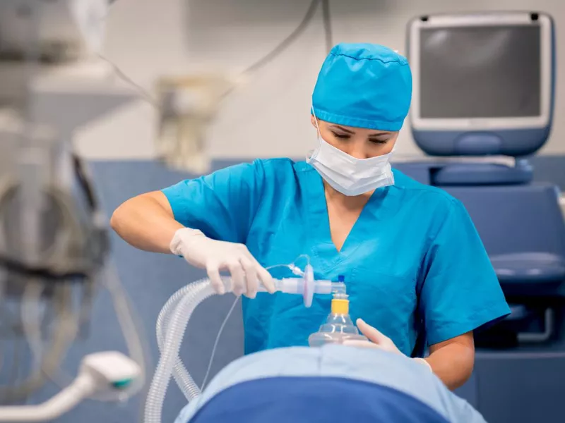 Nurse putting oxygen mask to patient during surgery