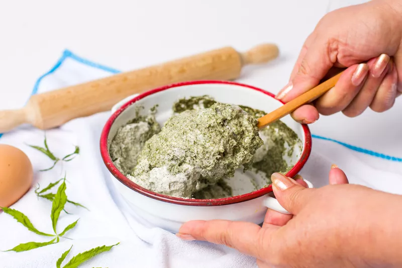 Woman preparing dough of mixed marijuana and wheat flour