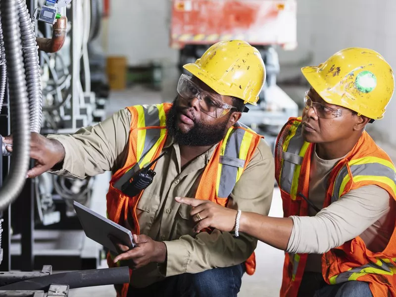 Two workers inspecting industrial refrigeration equipment