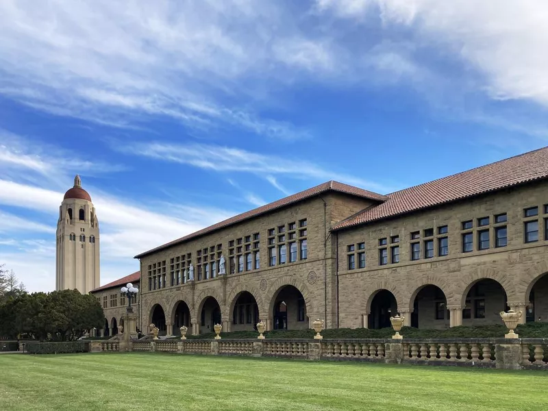 Hoover tower and Lane History Corner building on beautiful campus of Stanford University under blue sky