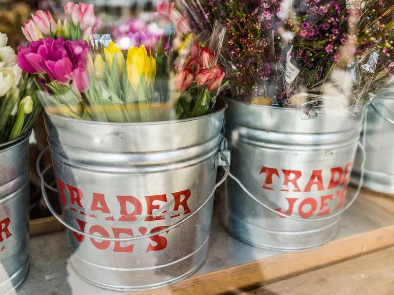 Buckets of flowers with Trader Joe's signs viewed from outside of store