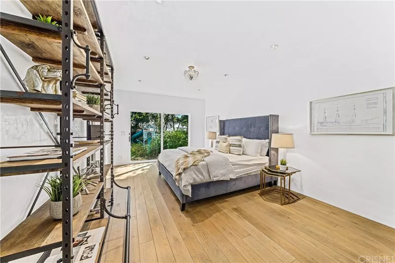 Joe Rogan's Home - Guest bedroom with shelves and wood floors