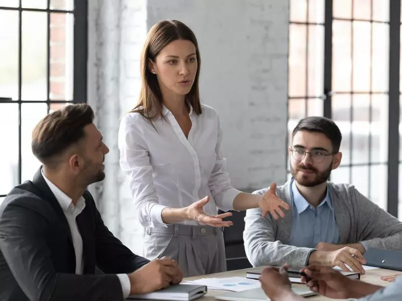 Attractive young mentor businesswoman conducts coaching in boardroom.