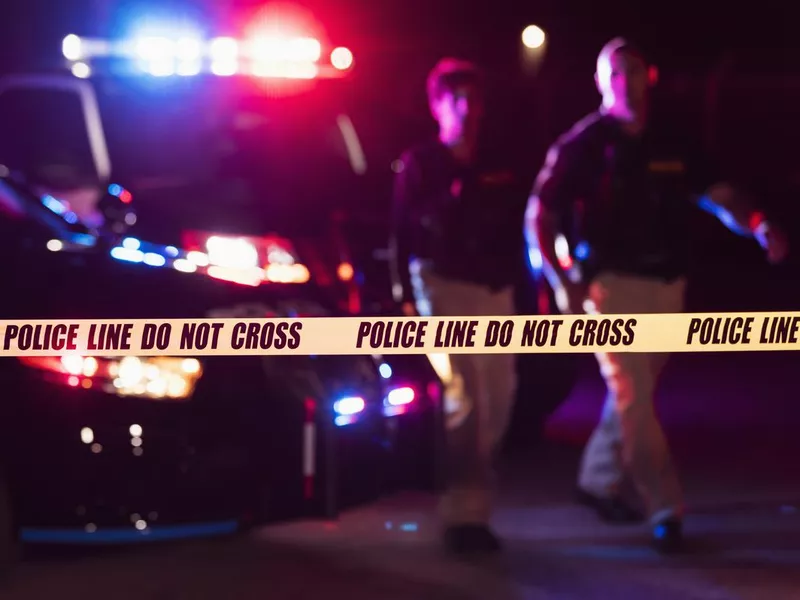 Two police officers behind crime scene tape