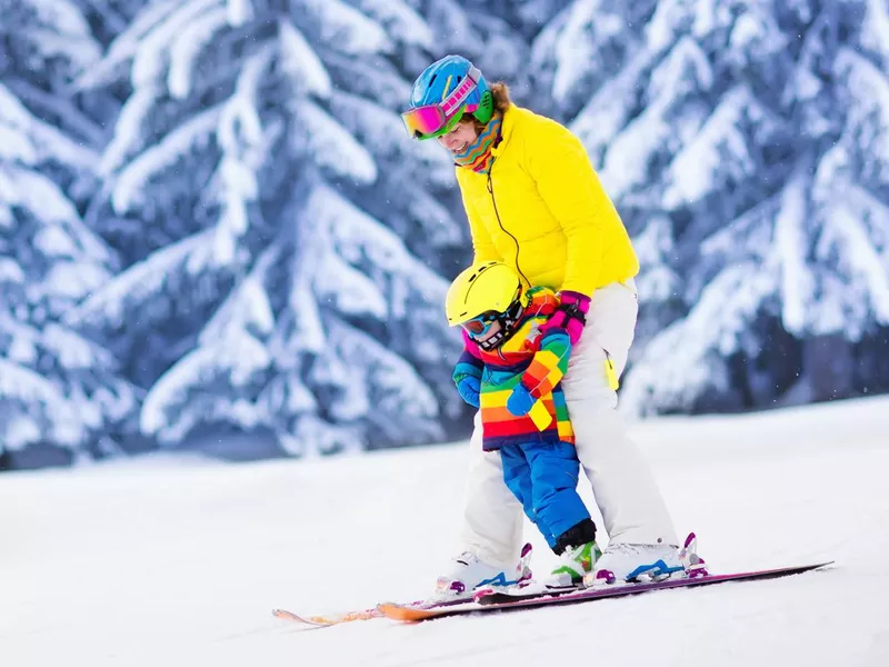 Active mother and little boy learning to ski