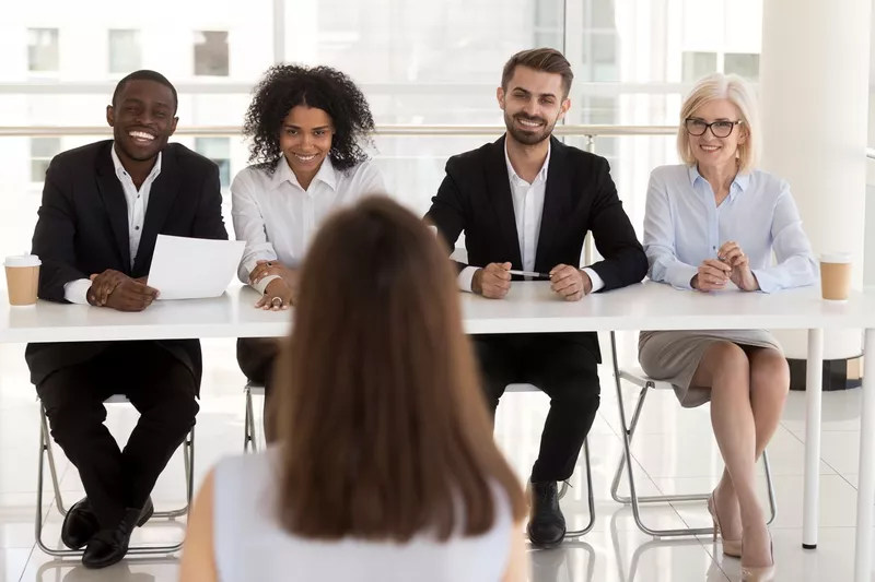 Several people interviewing a woman for a job