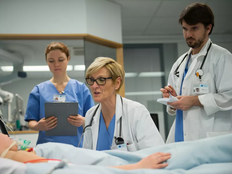 Doctor talking with patient while another doctor and physician assistant take notes