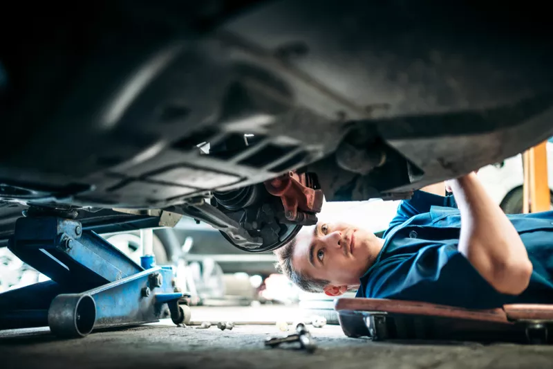 Car mechanic working under vehicle