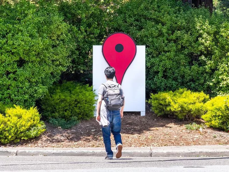 Person walking in front of the Google Maps Icon