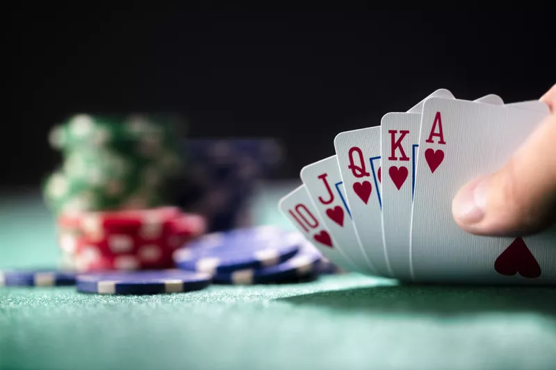 Player playing poker holding a winning royal flush hand of cards