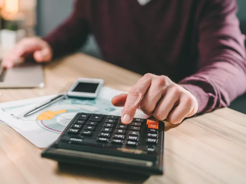 Man using a calculator and laptop