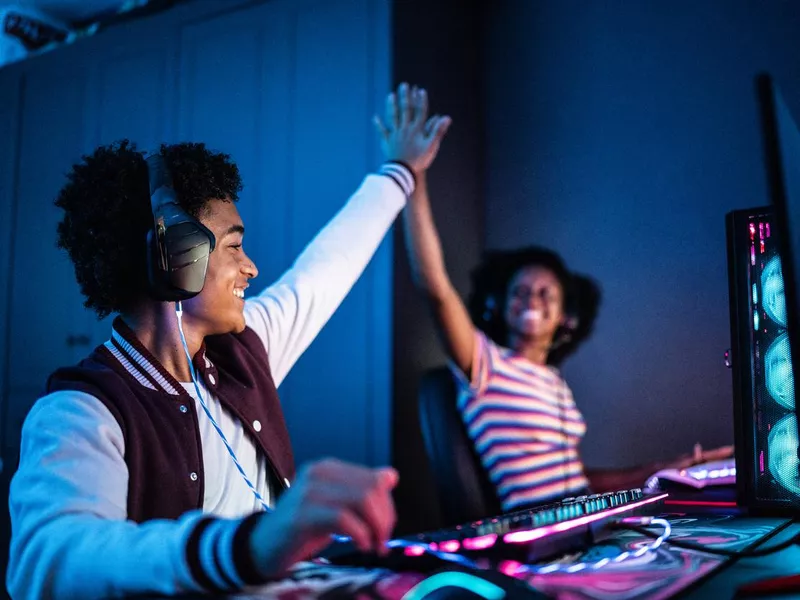 Friends doing a high five while playing online games at home