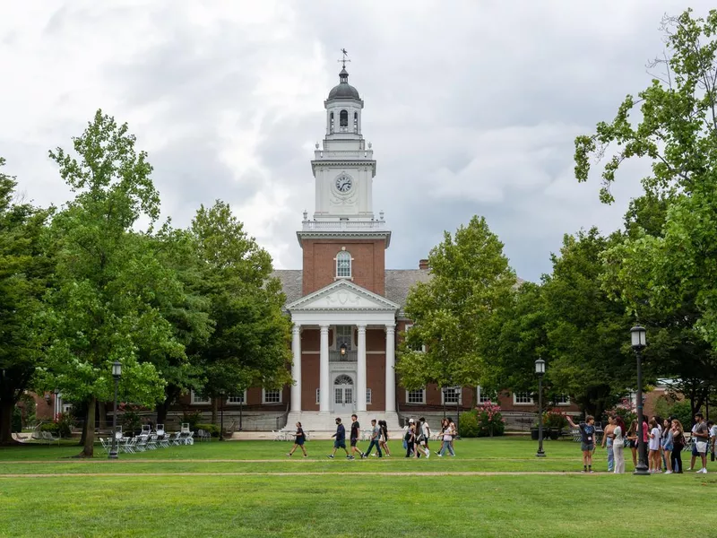 New students walk past Gilman Hall on the Johns Hopkins University campus