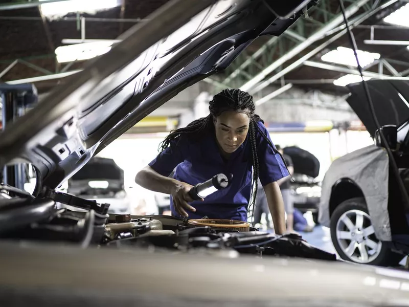 Woman repairing a car in auto repair shop