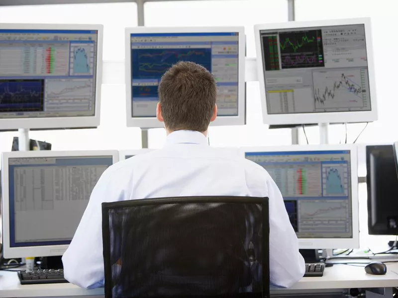 Stock trader looking at multiple monitors