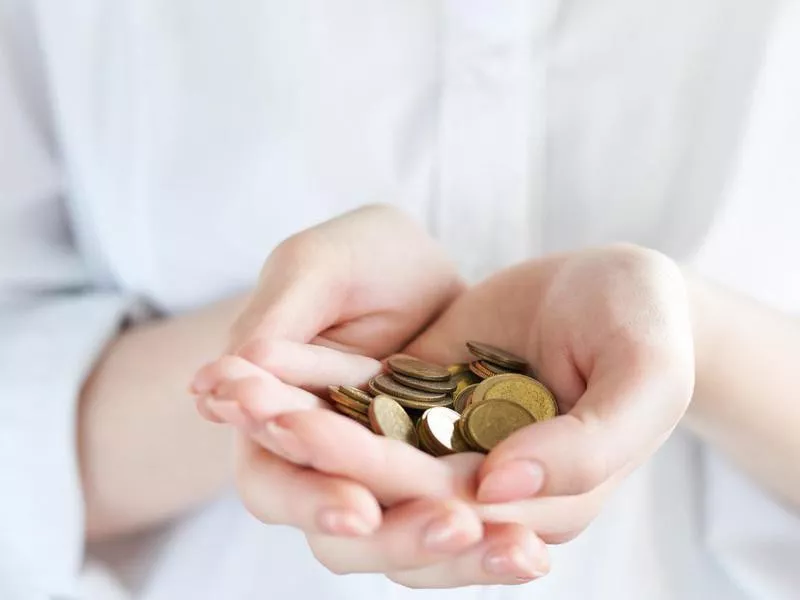 Handful of coins in palm hands isolated on white