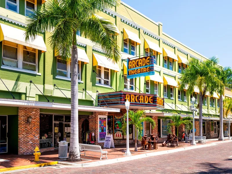 Florida Gulf of Mexico city street with retro vintage neon sign for Arcade theatre theater building with shops stores