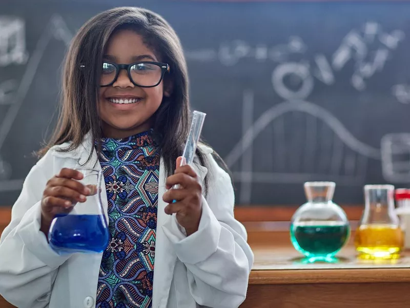 Little girl in a lab coat doing a science experiment in a lab