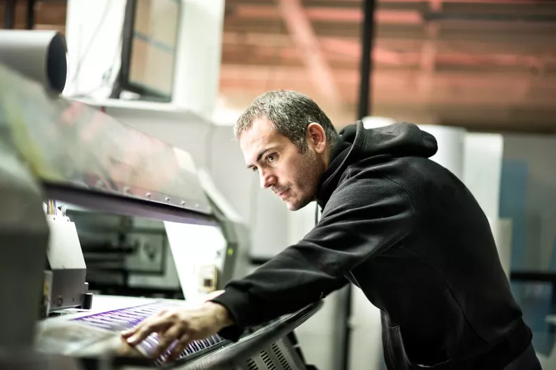 Male worker operating on industrial printer